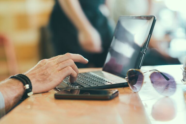 sunglasses hand smartphone desk